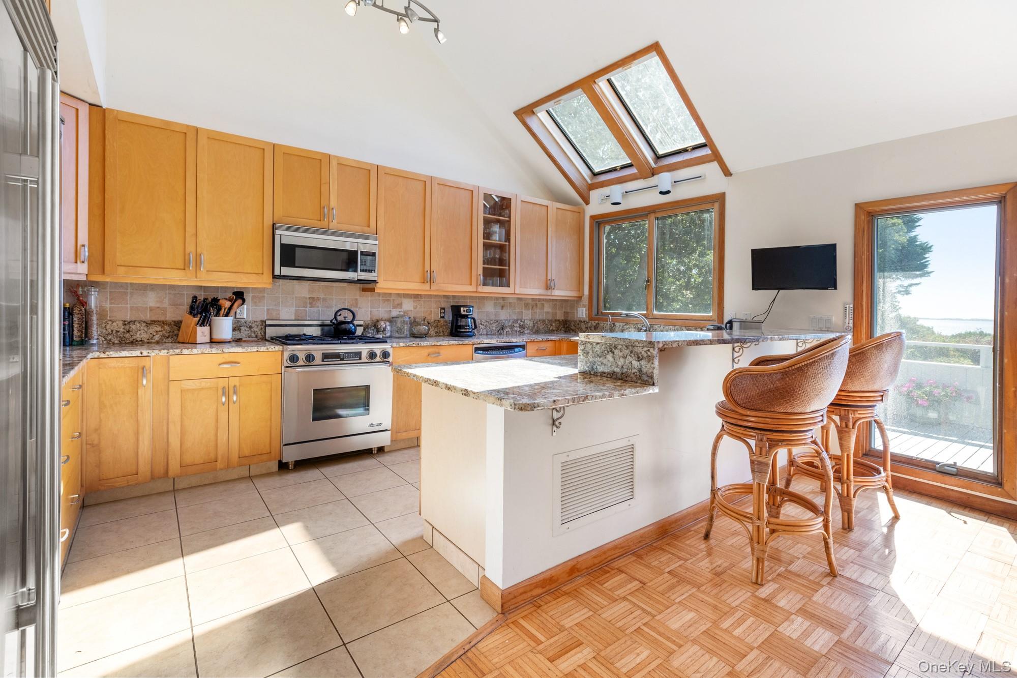 29 Kenwood Road Southampton, NY 11968 - Photo 13 of 35 a kitchen with stainless steel appliances a stove a sink a microwave a dining table and chairs