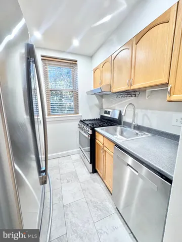 a kitchen with stainless steel appliances granite countertop a sink a stove a refrigerator and a window