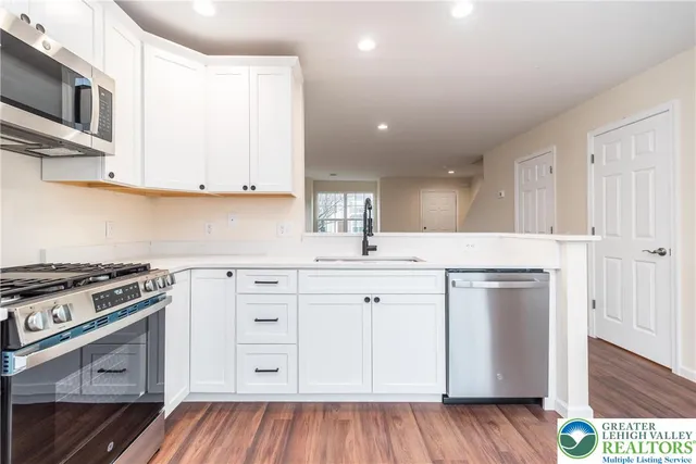 a kitchen with stainless steel appliances granite countertop a stove a sink and a microwave