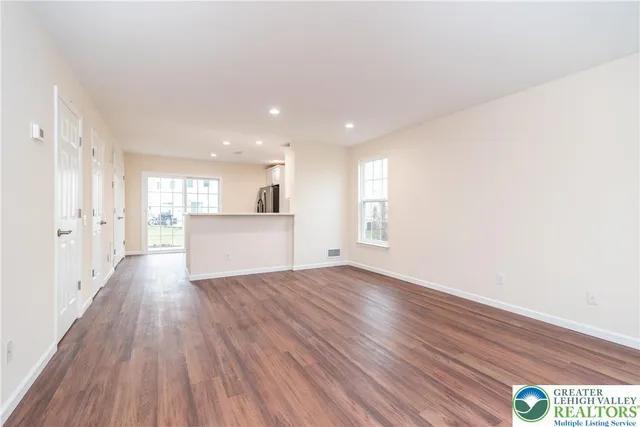 a view of a big room with wooden floor and windows