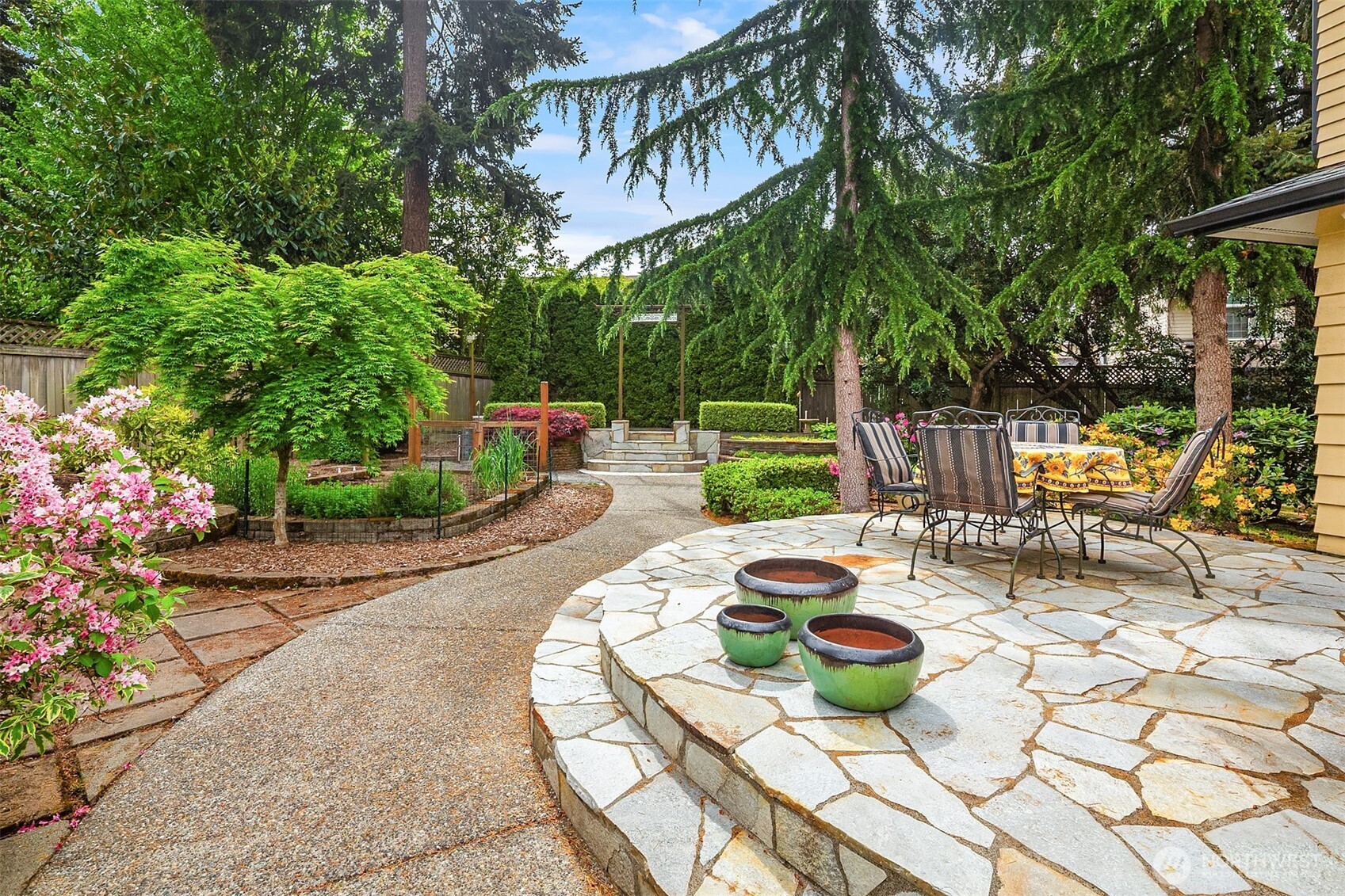 7732 195th Street Southwest Edmonds, WA 98026 - Photo 27 of 39 a view of a patio with table and chairs potted plants and large tree
