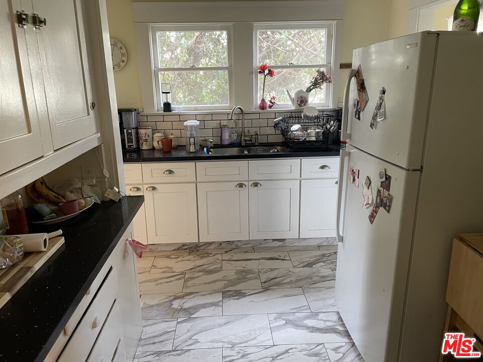 1920 South Rimpau Boulevard Los Angeles, CA 90016 - Photo 5 of 25 a kitchen with stainless steel appliances a refrigerator sink and white cabinets