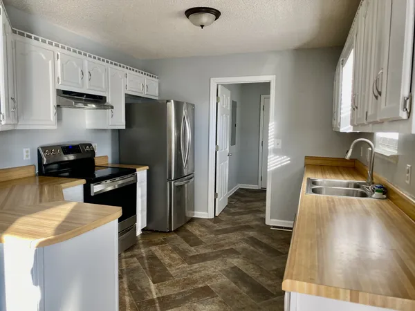 a kitchen with granite countertop a refrigerator a stove and a sink