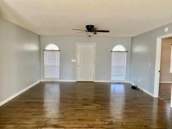 a view of an empty room with window and wooden floor