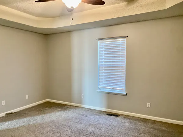 an empty room with a window and a ceiling fan