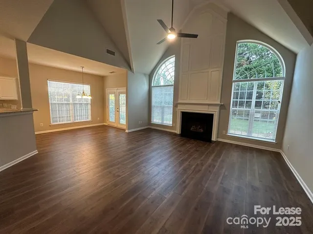 an empty room with wooden floor fireplace and windows