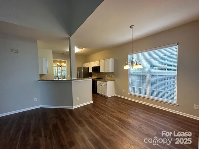 a view of a kitchen and an empty room with wooden floor and a kitchen