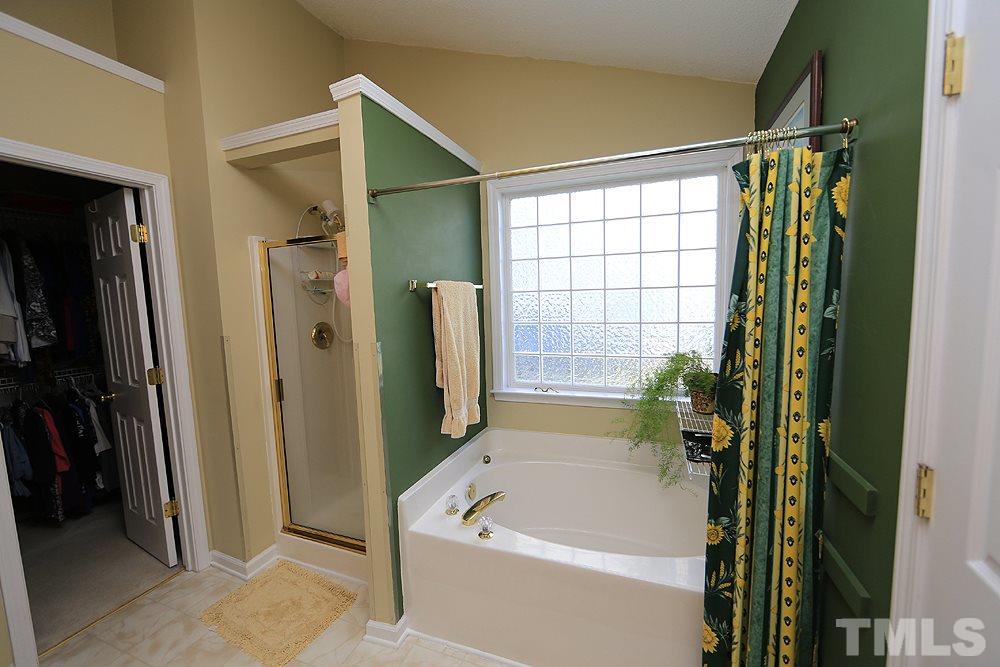 4707 Drewbridge Way Raleigh, NC 27604 - Photo 19 of 28 a bathroom with a bathtub a shower and a window