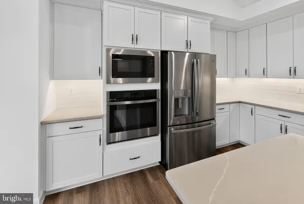 a kitchen with a refrigerator stainless steel appliances wooden floor and cabinets