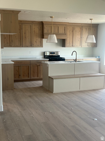 4740 West 25 North West Point, UT 84015 - Photo 9 of 15 Spacious kitchen featuring wood-finish flooring, custom cabinetry, white countertops, built-in stainless steel appliances, and a central island with integrated seating