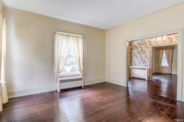 an empty room with wooden floor fireplace and windows