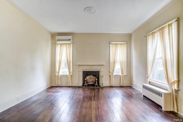an empty room with wooden floor fan and windows