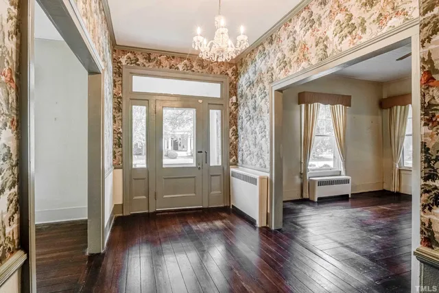 an empty room with wooden floor fireplace and windows
