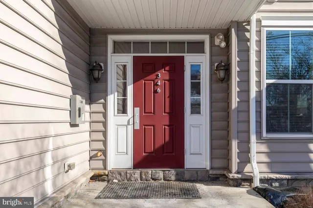 a view of a brick house with a red door and a large window