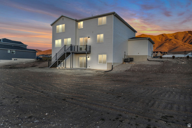 2821 Scarlet Road, Unit 149 Eagle Mountain, UT 84005 - Photo 28 of 28 Our two-story "Magnolia" featuring a multi-level deck with dark railings, a ground-level patio door, and multiple windows across three stories. Nearly flat back yard of the .75 acre lot taken from the southwest corner of property.