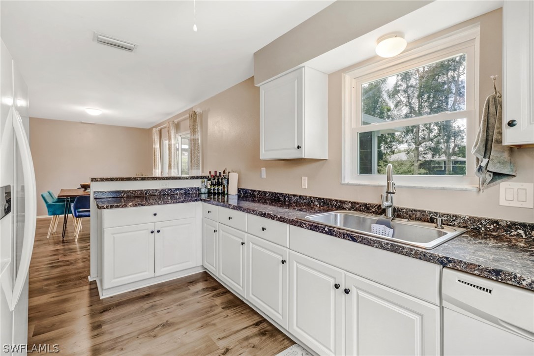 8454 Wren Road Fort Myers, FL 33967 - Photo 8 of 23 a kitchen with granite countertop white cabinets white appliances a sink and a large window