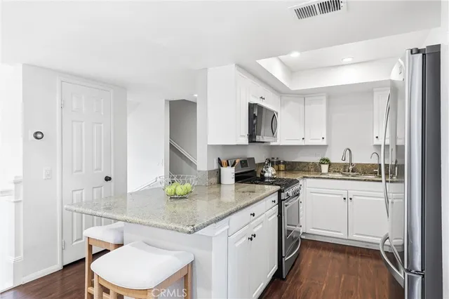 a kitchen with a sink a stove cabinets and wooden floor
