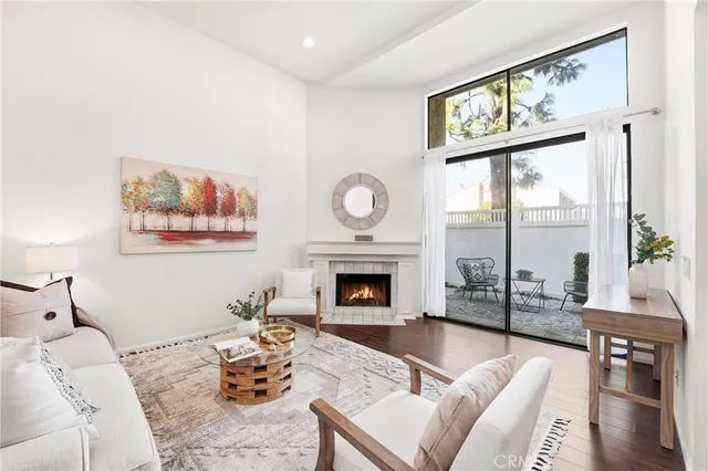 a living room with furniture a fireplace and floor to ceiling windows