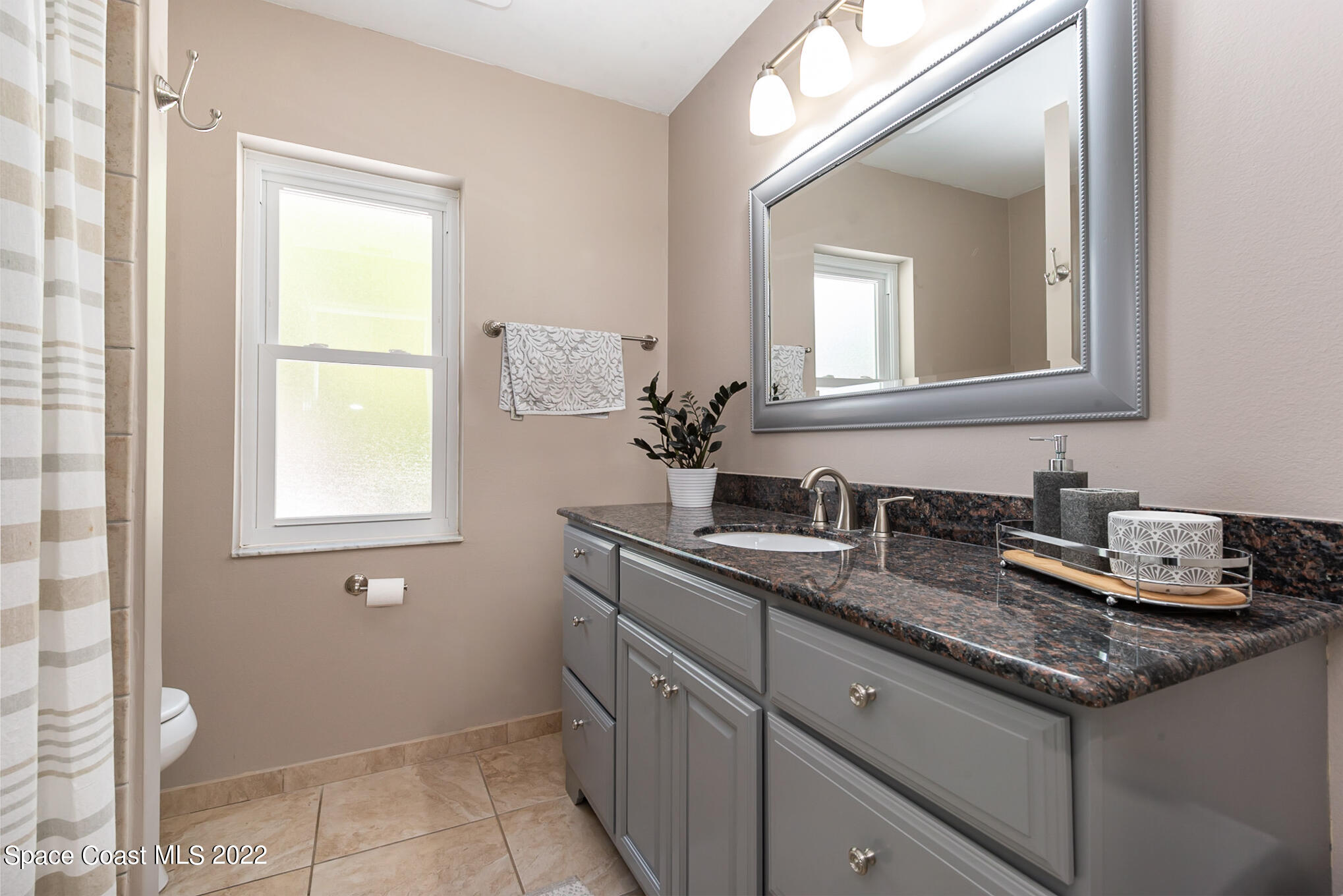 395 Rio Lane Indialantic, FL 32903 - Photo 34 of 40 a bathroom with a granite countertop sink a toilet and mirror
