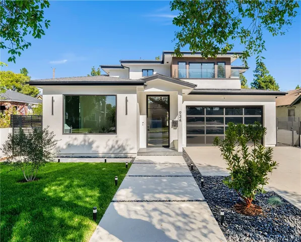 a front view of a house with a yard and potted plants