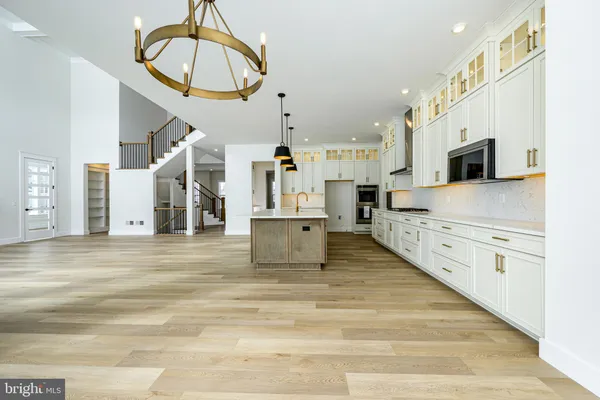 a large white kitchen with stainless steel appliances granite countertop a stove a sink dishwasher and white cabinets with wooden floor