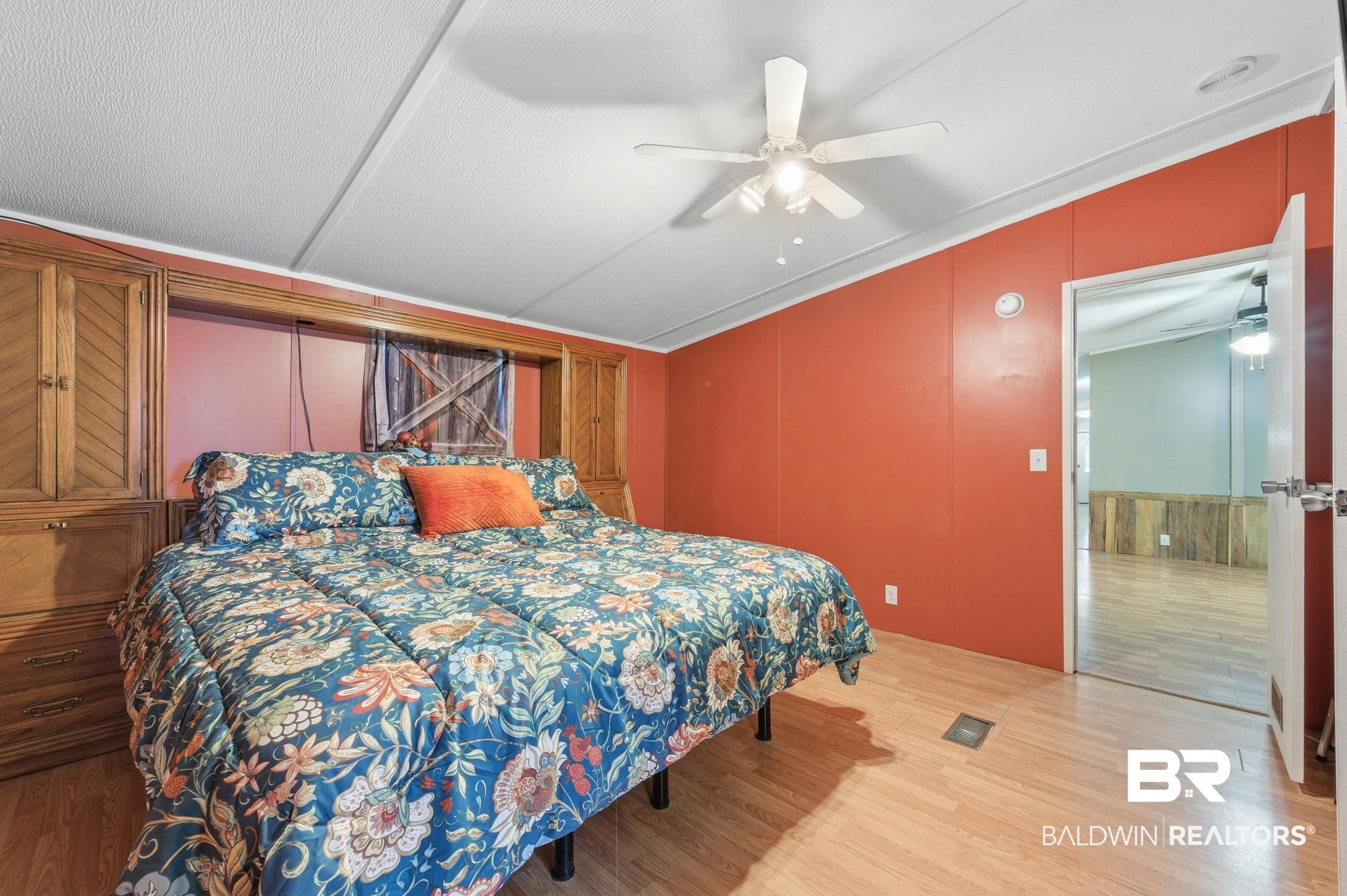 926 Tumbling Lane Atmore, AL 36502 - Photo 28 of 56 Bedroom featuring wood-finish flooring, built-in cabinetry, a ceiling fan, and accent wall paneling