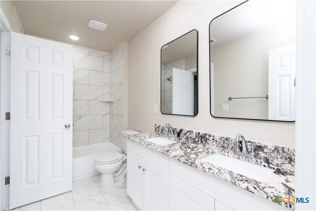 a bathroom with a granite countertop sink mirror and toilet