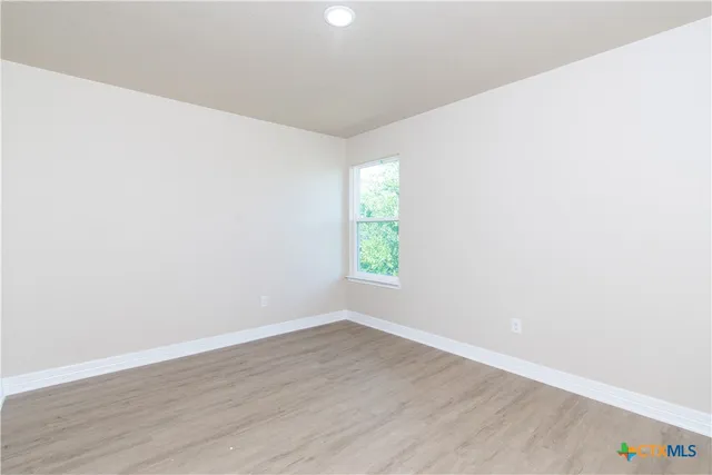 an empty room with wooden floor and window