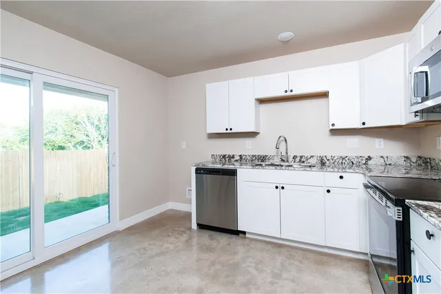 a kitchen with granite countertop white cabinets and white appliances