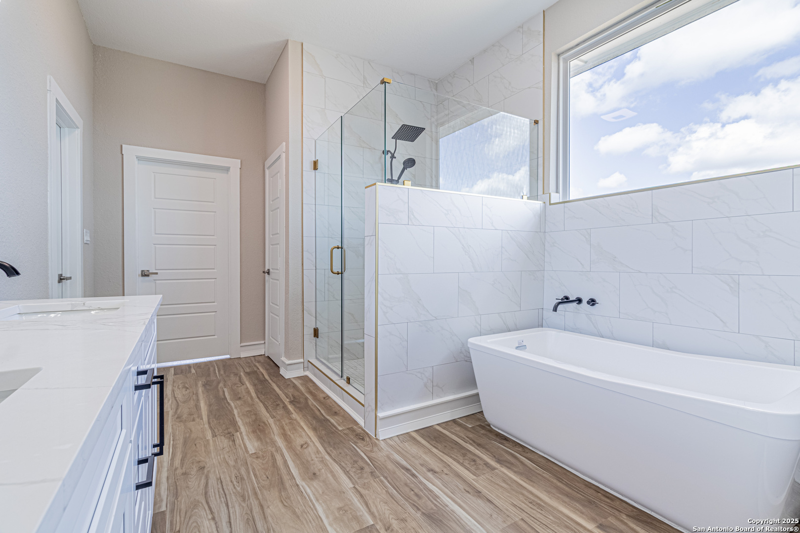 16923 Rancho Escondido Atascosa, TX 78002 - Photo 18 of 35 a bathroom with a tub a sink and wooden floor