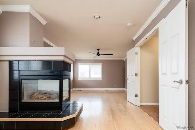 a living room with stainless steel appliances wooden floor and a fireplace