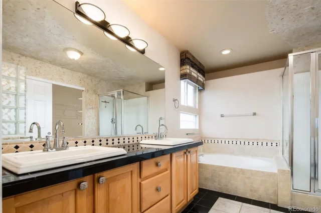 a bathroom with a sink double vanity granite tub shower and a mirror
