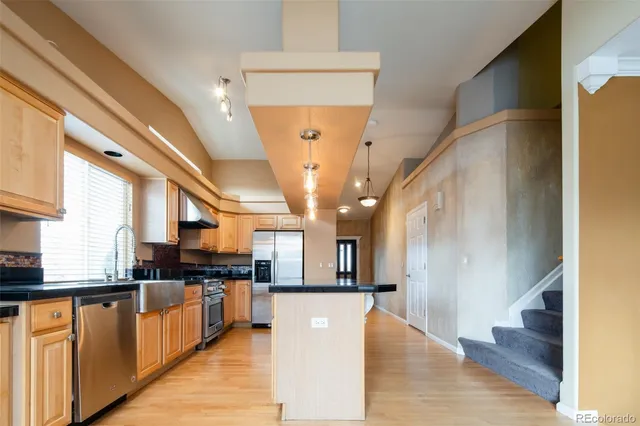 a view of a living room with stainless steel appliances kitchen island granite countertop wooden floor view and a window