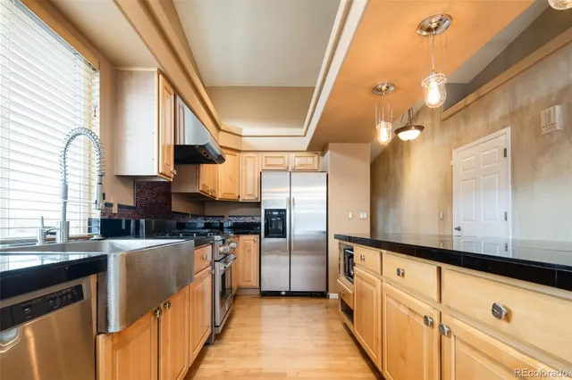 a kitchen with stainless steel appliances granite countertop a sink and a refrigerator