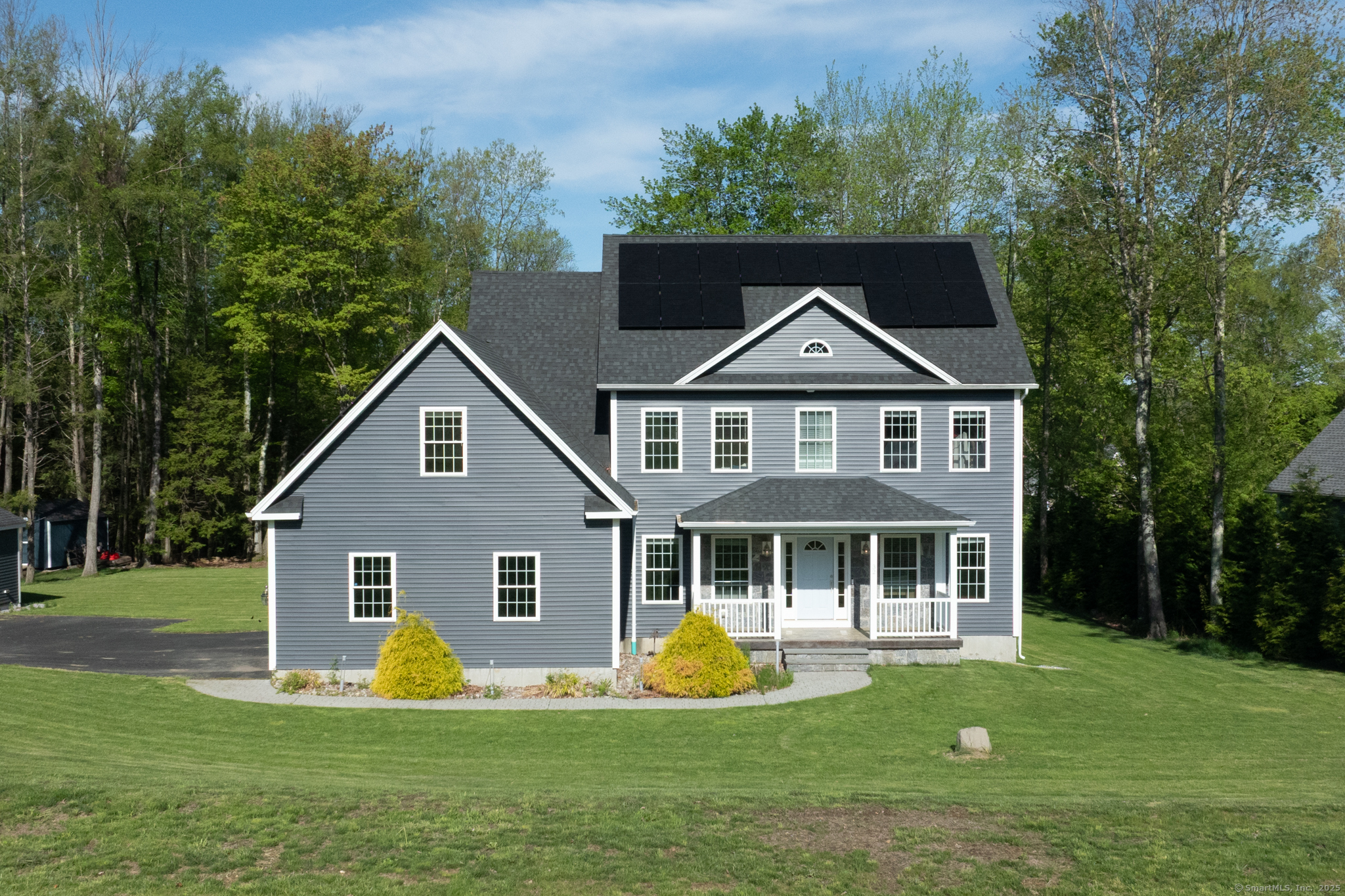 a front view of a house with garden and trees