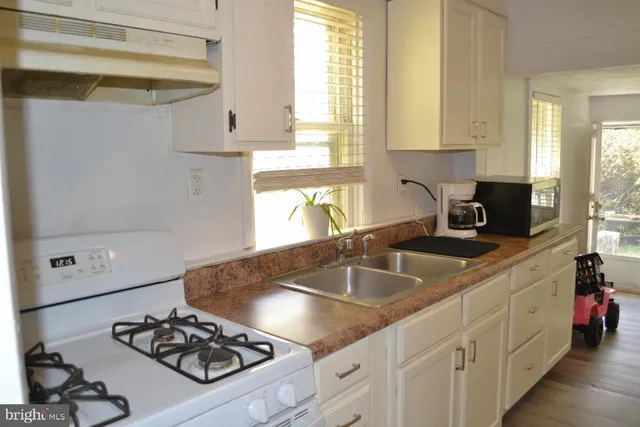 a kitchen with sink a stove and white cabinets