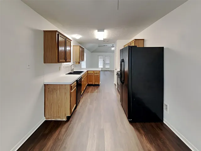 a kitchen with granite countertop wooden cabinets a refrigerator and a sink