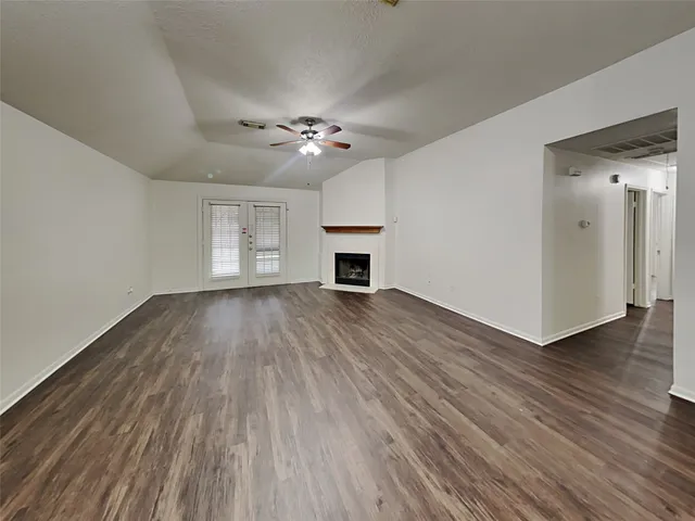 a view of empty room with wooden floor and ceiling fan