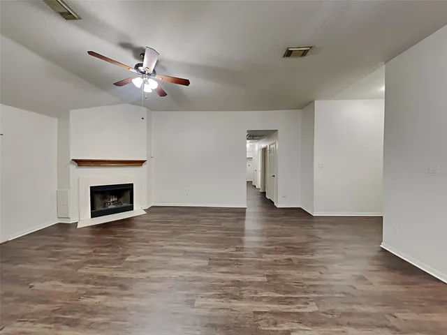 a view of an empty room with wooden floor fireplace and a window