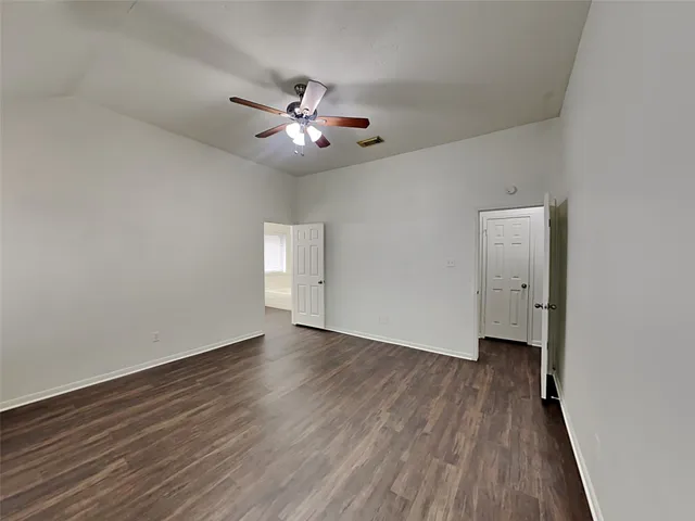 an empty room with wooden floor ceiling fan and window