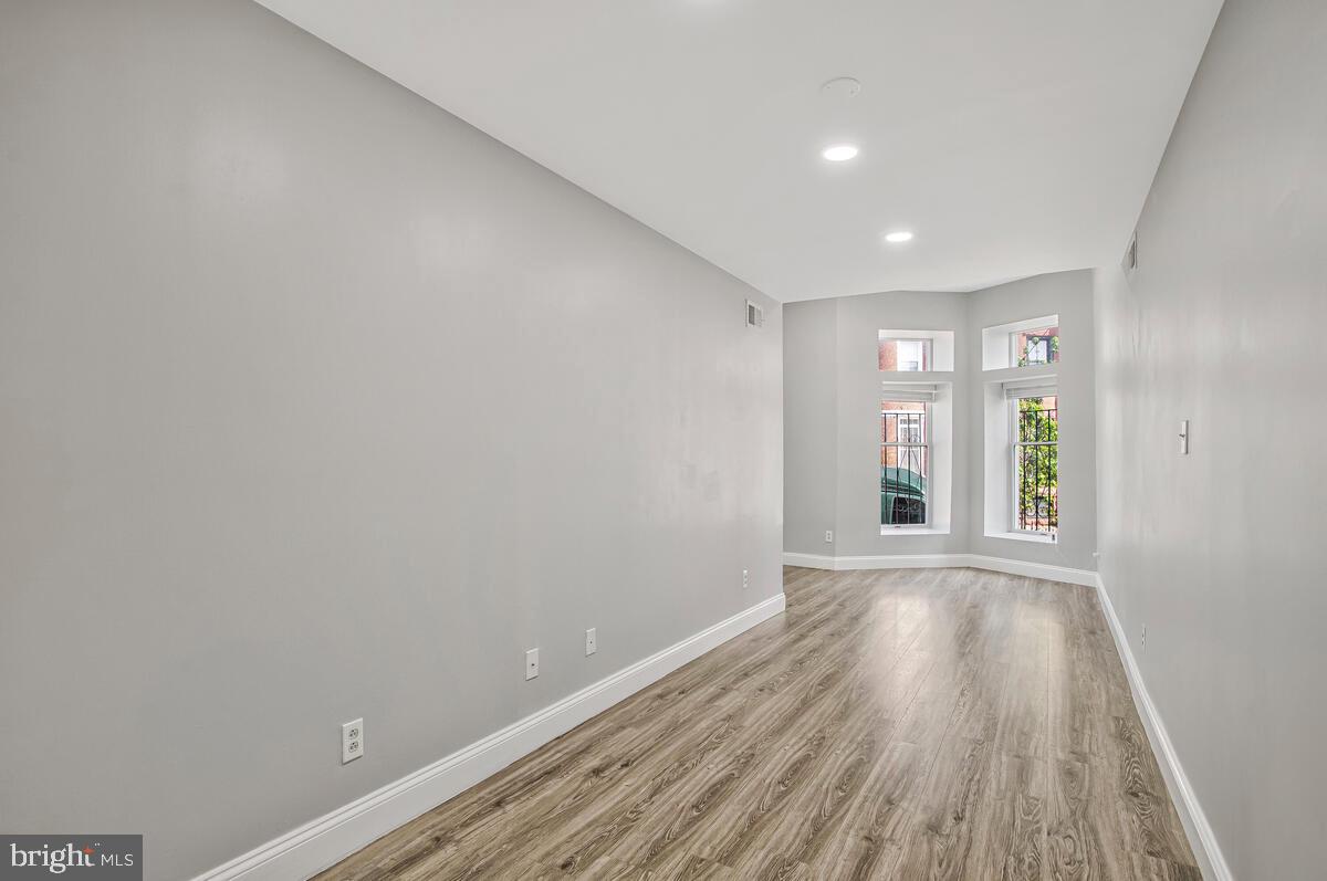 823 Newington Avenue Baltimore, MD 21217 - Photo 6 of 30 a view of an empty room with wooden floor and a window