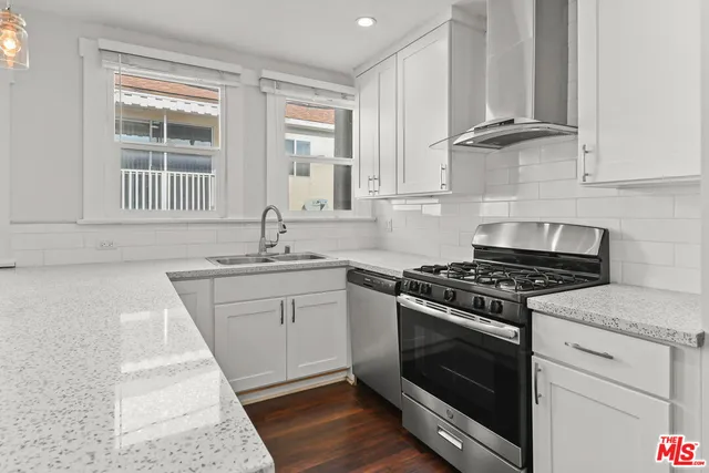 a white kitchen with granite countertop a stove top oven