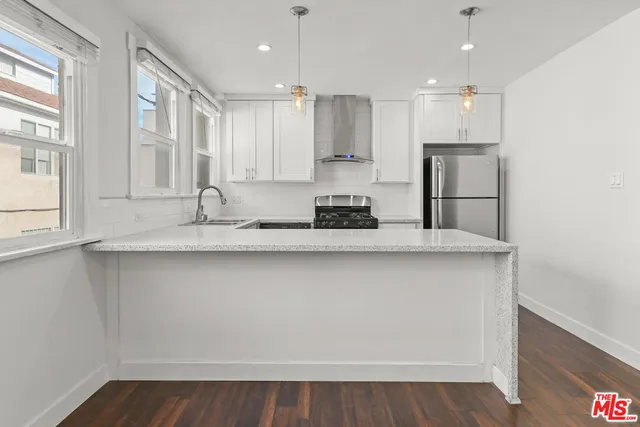 a kitchen with stainless steel appliances granite countertop a sink a stove a refrigerator and cabinets with wooden floor