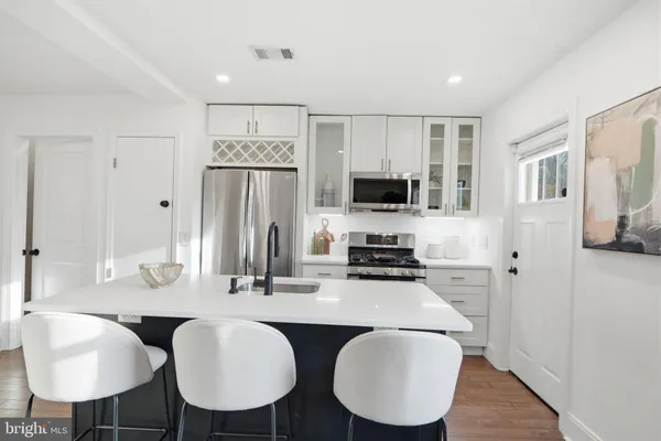 a kitchen with stainless steel appliances granite countertop a dining table chairs refrigerator and sink