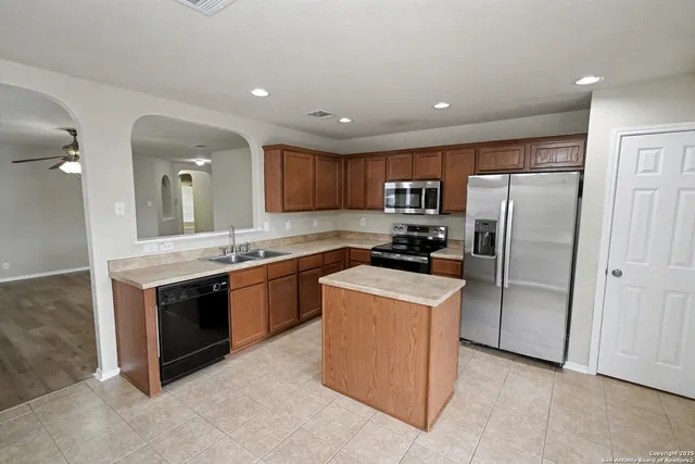 a large kitchen with stainless steel appliances granite countertop a stove a refrigerator and a sink