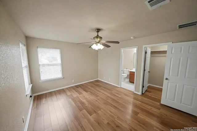 a view of empty room with wooden floor and fan