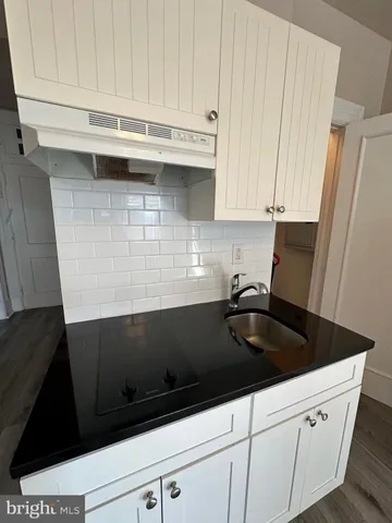 a kitchen with granite countertop white cabinets and sink
