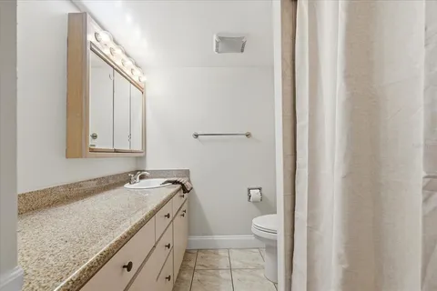 a bathroom with a granite countertop sink a toilet and a mirror