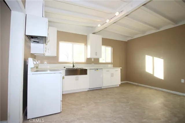 a kitchen with granite countertop white cabinets and white appliances