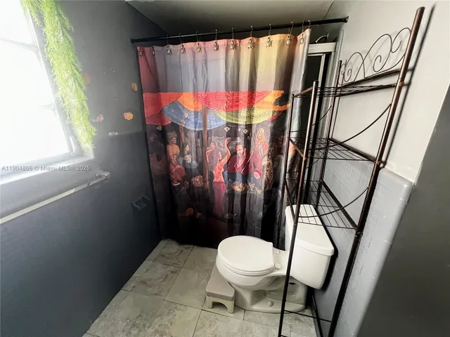 a bathroom with a toilet and a shower curtain